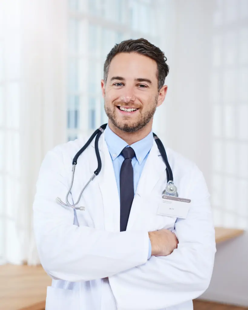 Middle-aged male doctor with a white coat and stethoscope around his neck smiling at the camera.